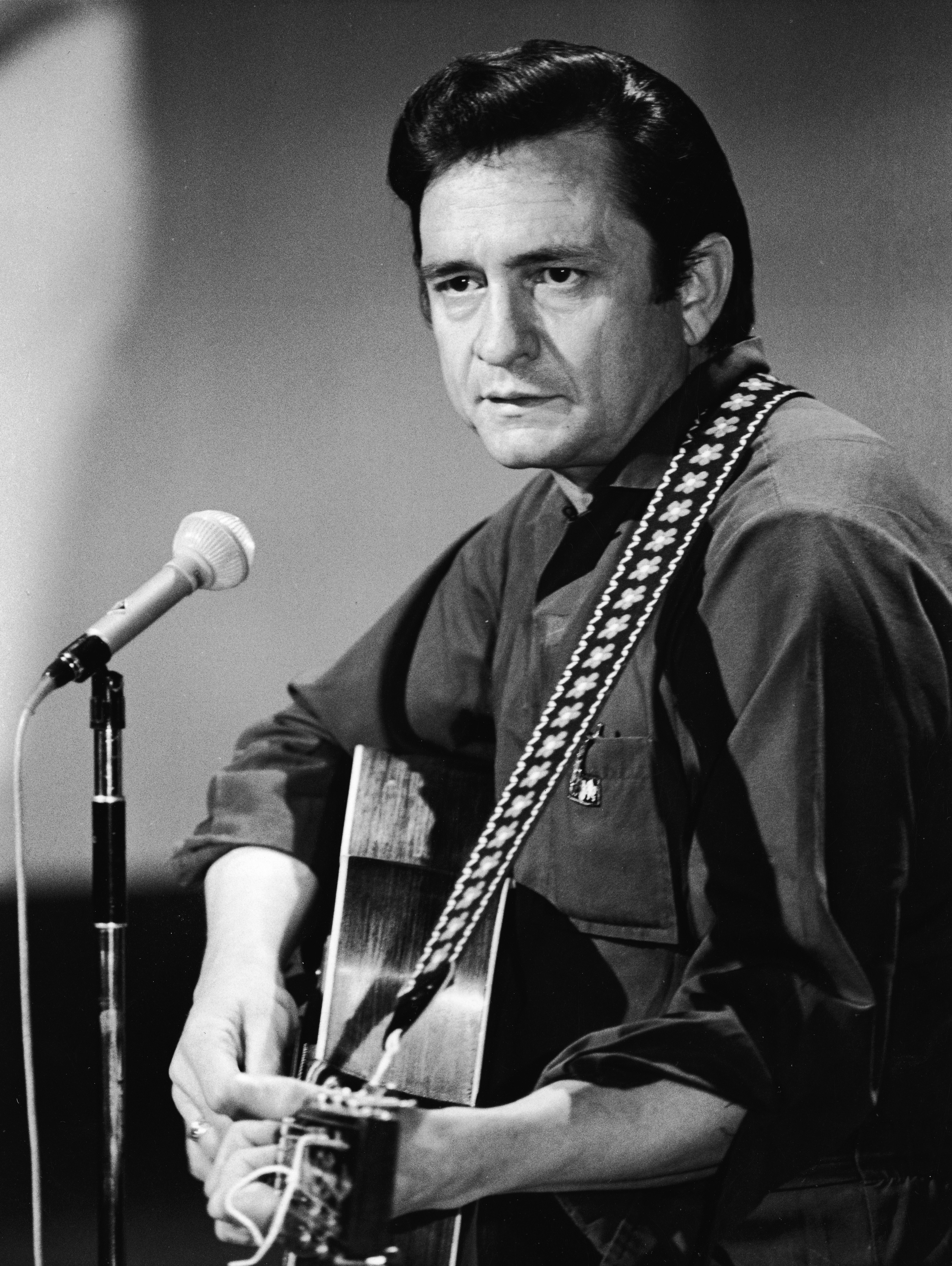 American country singer and songwriter Johnny Cash (1932 - 2003) plays acoustic guitar in a still from his television variety series,