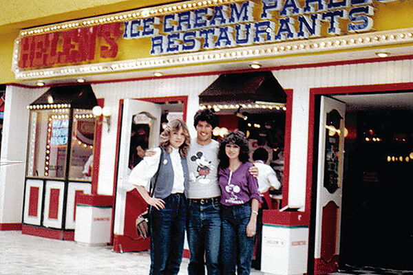 Two women and a man standing outside a Helen's ice cream parlor and restaurant