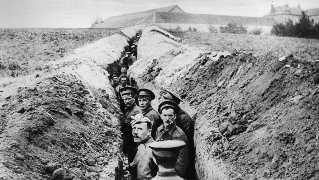 Soldiers lined up in a narrow trench during World War I