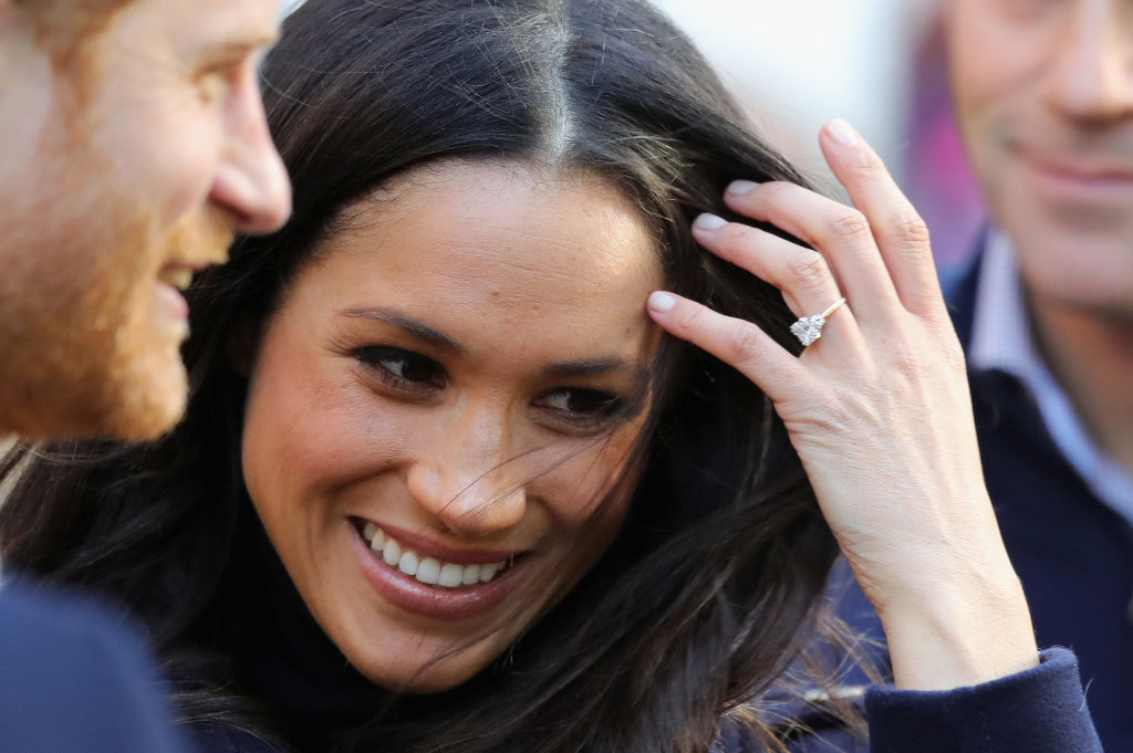 Prince Harry and Meghan Markle while Markle shows her diamond ring 