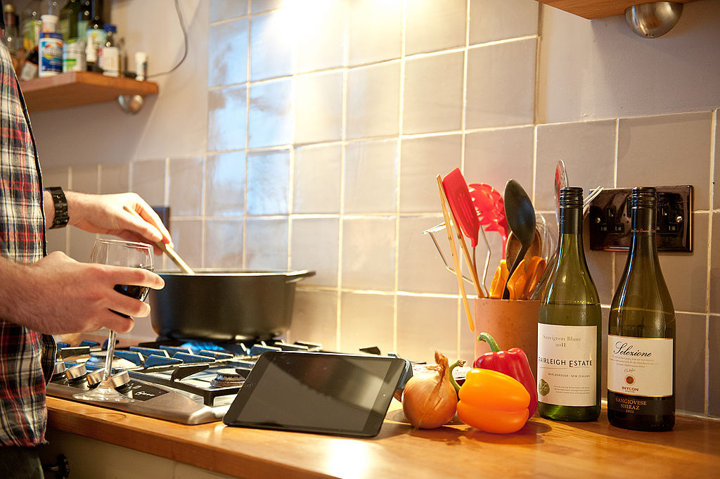 A man using an Apple iPad Mini tablet computer in a kitchen setting-162792832