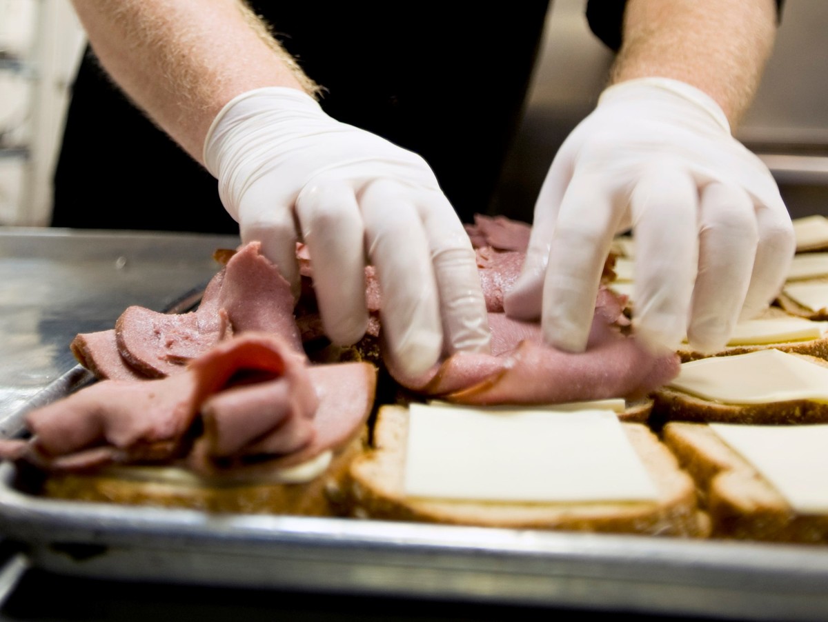 A chef prepares ham and cheese sandwhiches