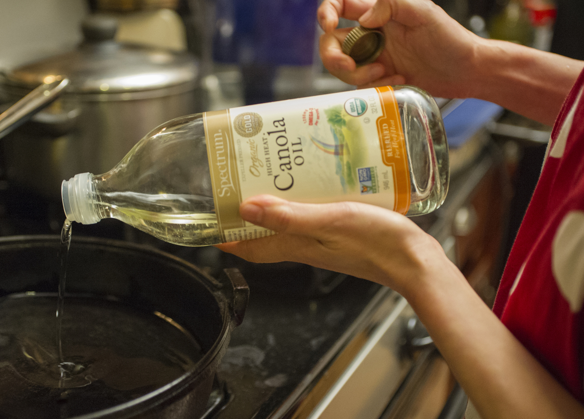 Chef cooks a meal while pouring canola oil into a pan