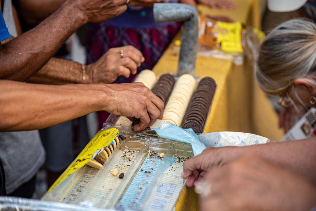 People grab cookies from a plastic package.