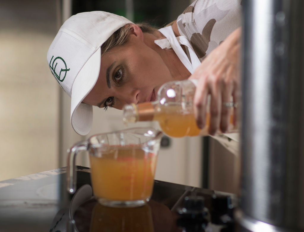 A woman pours apple cider vinegar into a measuring cup.