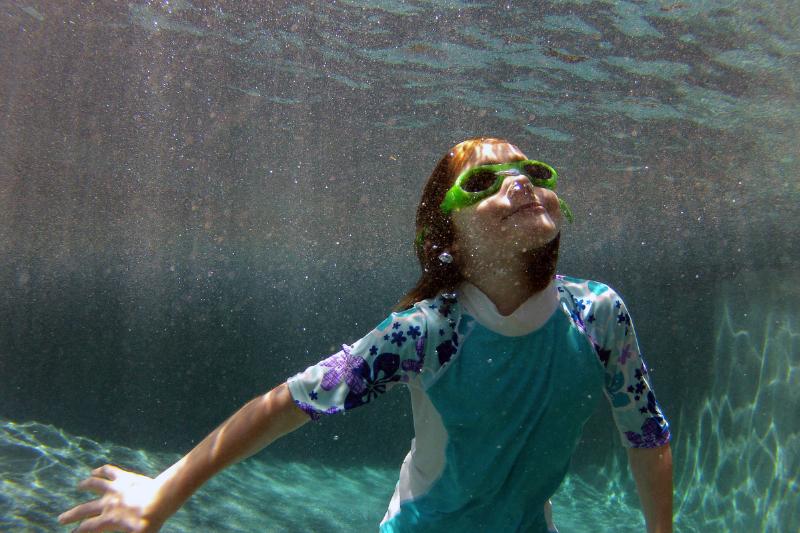 girl swimming in backyard pool