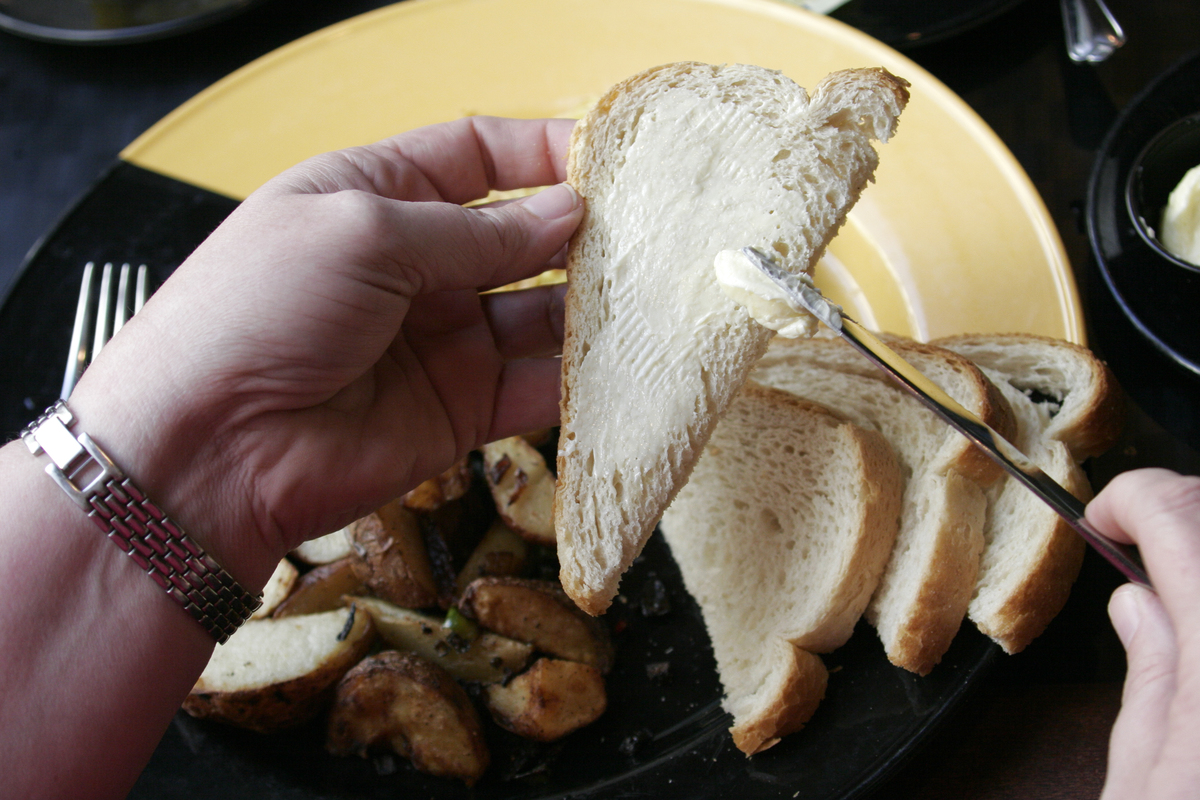 Butter being spread on a slice of bread 