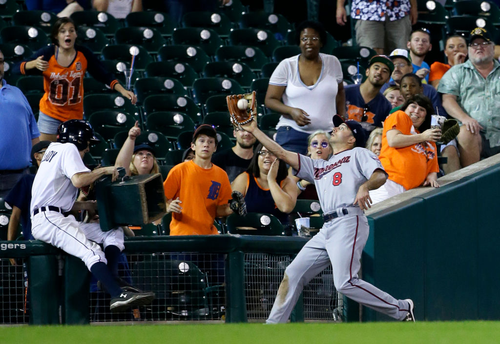 A ball boy tumbles back against the railing as Zack Granite #8 of the Minnesota Twins catches