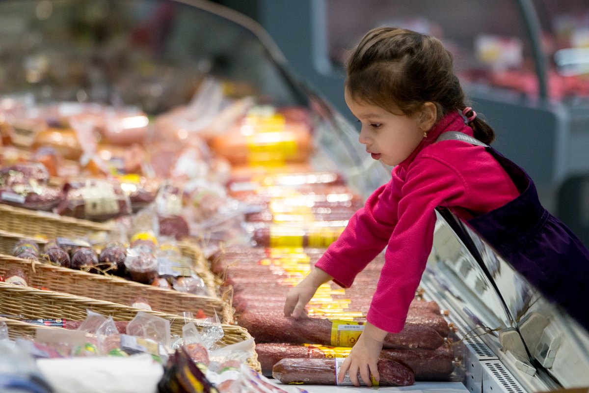 A girl reaching for salami at a Lenta supermarket in Russia