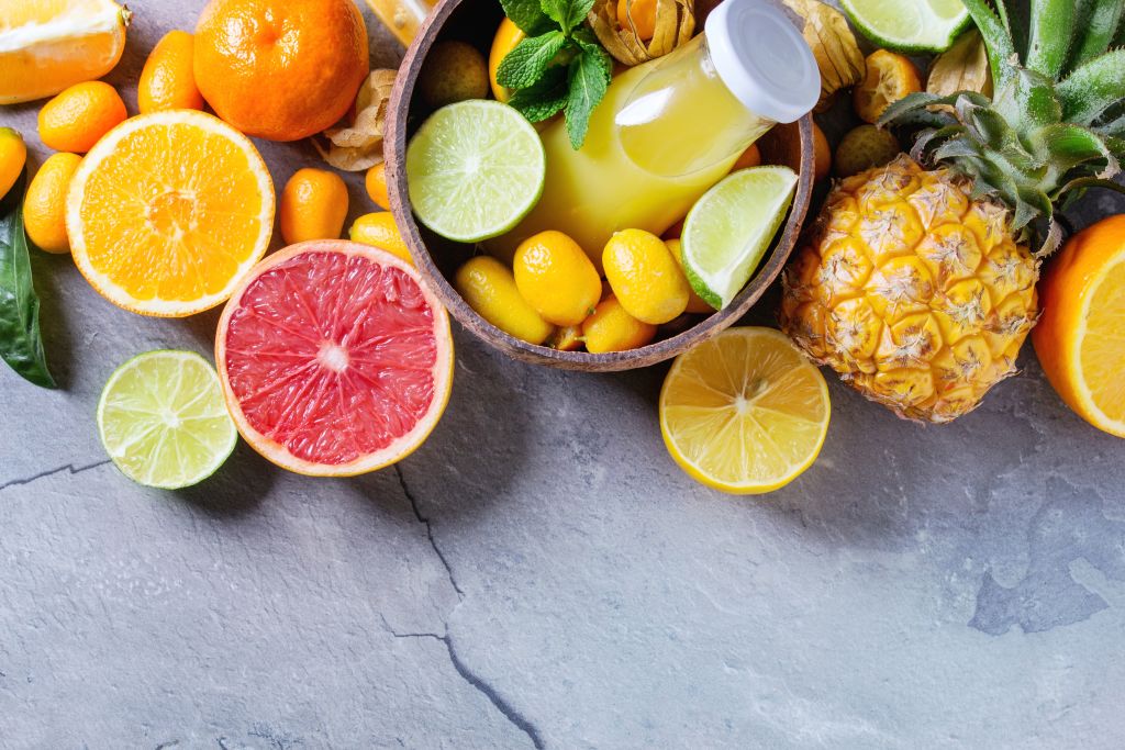 Variety of whole and sliced citrus fruits pineapple, grapefruit, lemon, lime, kumquat, clementine and physalis