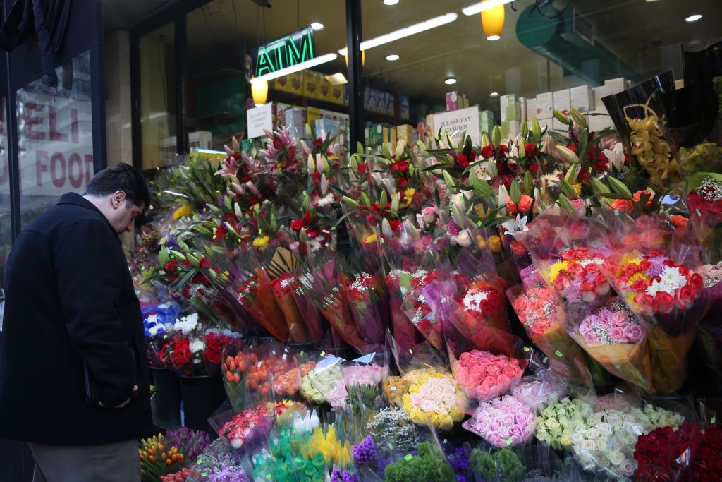 a man looking at the pre-arranged flower selection in front of a store