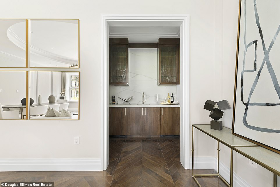 An entryway off of the living room reveals a wet bar with cabinetry, a countertop and sink.