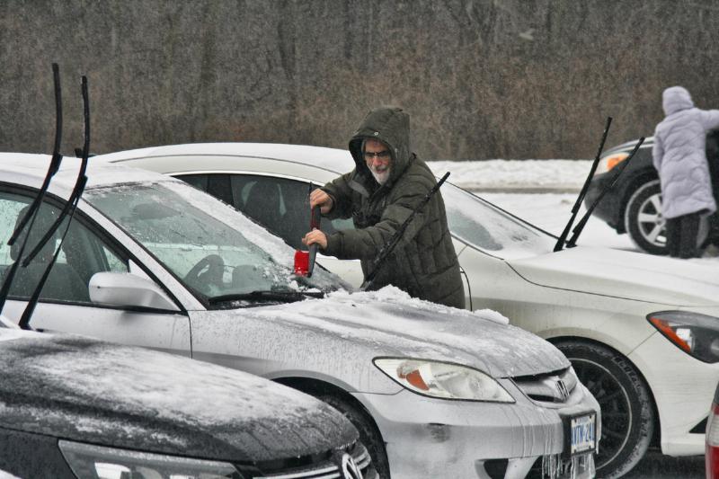 Man scrapes ice from his windshield as snow, freezing rain and ice pellets hit the Greater Toronto Area