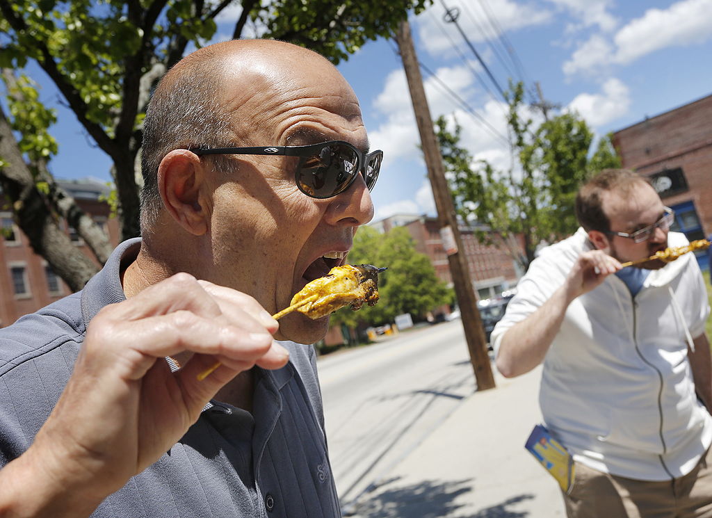 A man bites into a dogfish skewer