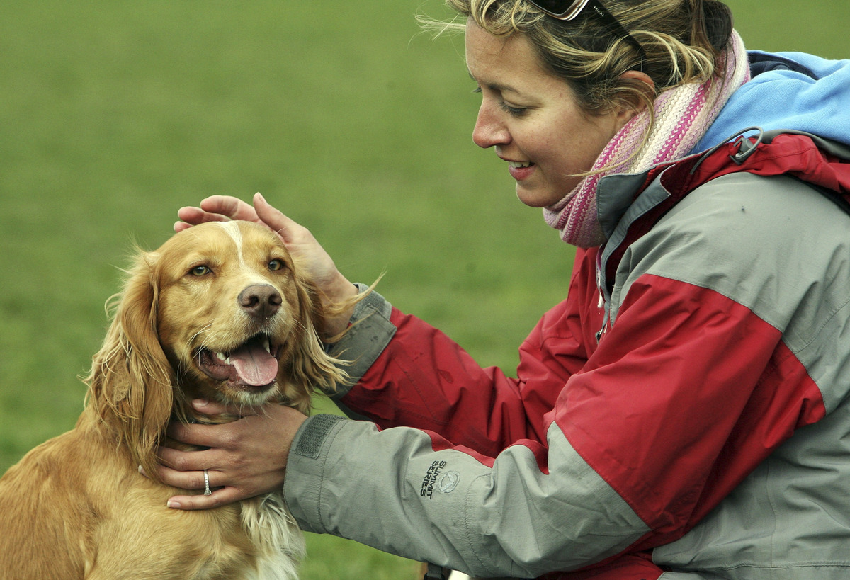 Dog owner, Fen Reilly, strokes her dog Larry in Battersea Park in London
