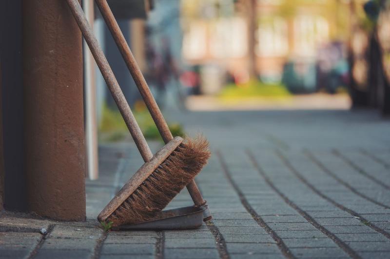 Broom leans against a wall outside of a storefront