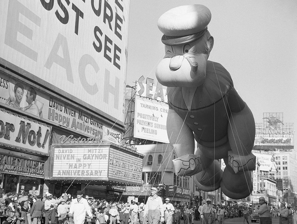 Popeye balloon floating over a large crowd
