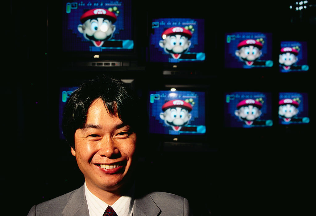 Man standing in front of TV screens showing Mario