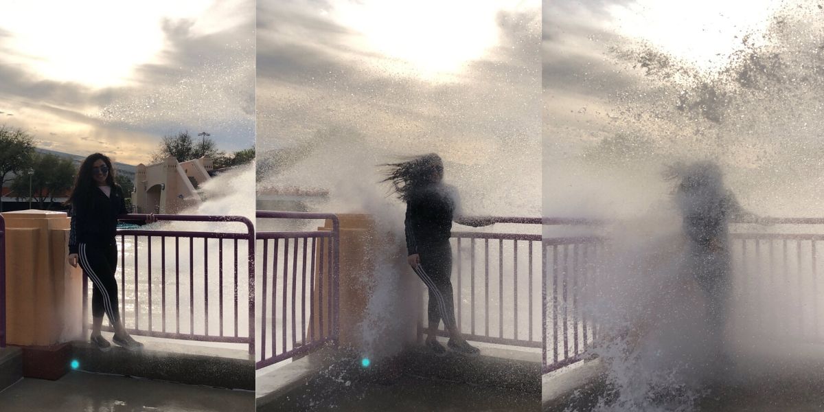 girl soaked by a wave while taking picture