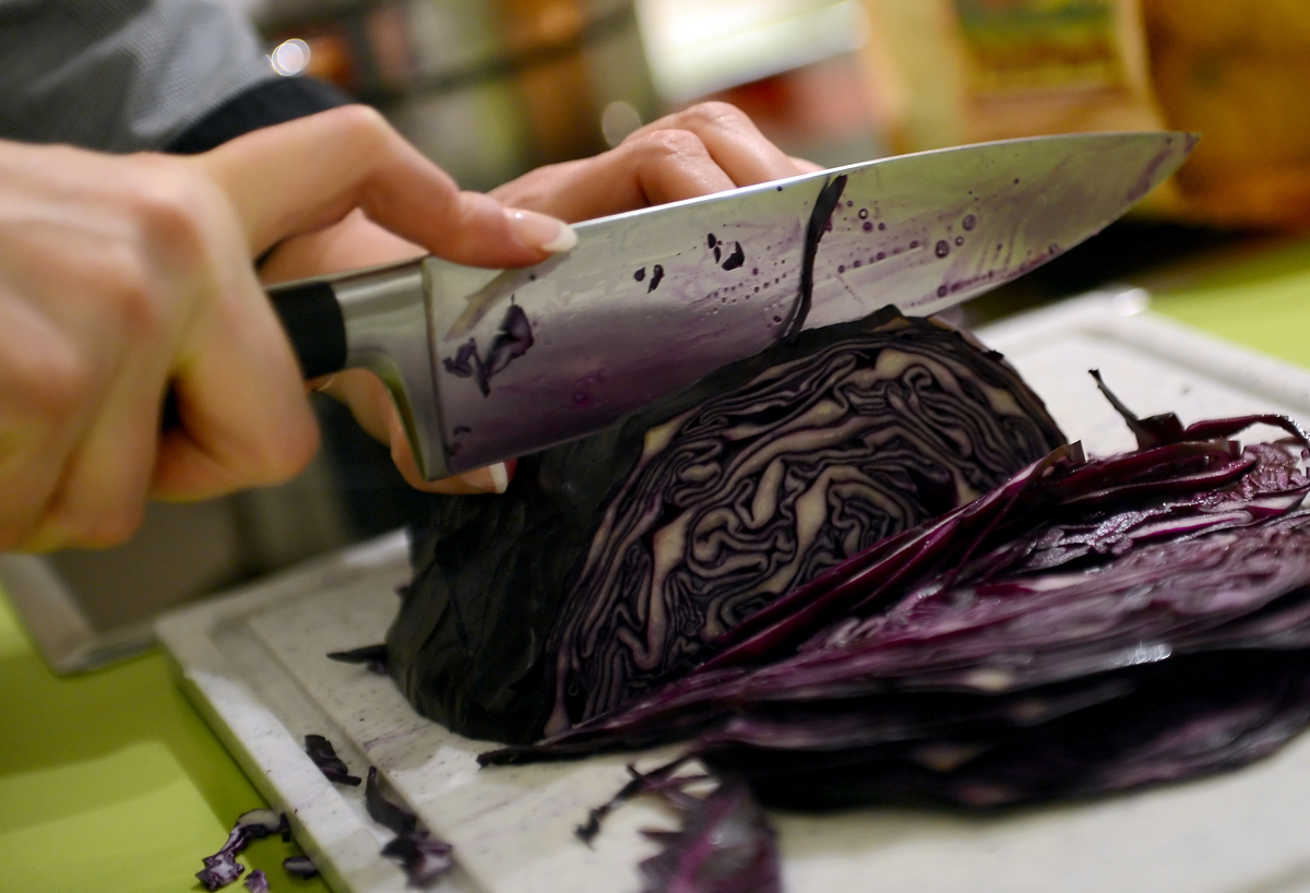 A participant of a cooking class cuts red cabbage for a vegan Christmas dinner.