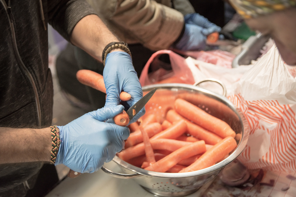 An activist in Athens cuts carrots to prepare meals for people in need.
