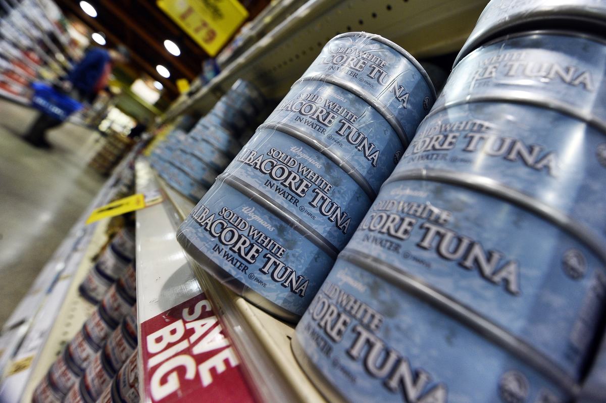 Canned tuna lines the shelves of a grocery store.