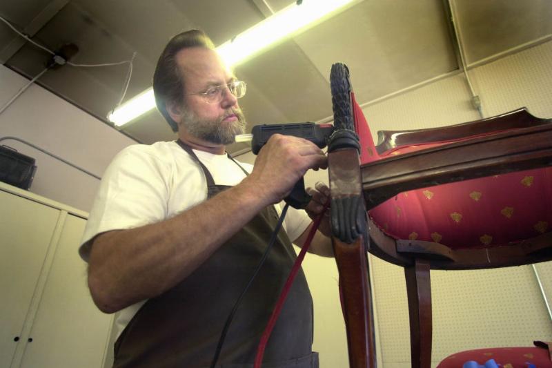 Man using a hot glue gun on a chair 