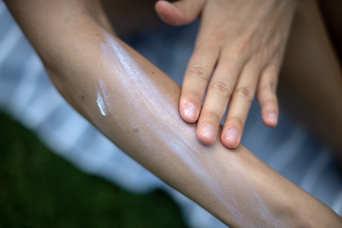 A woman applies lotion to her arm.