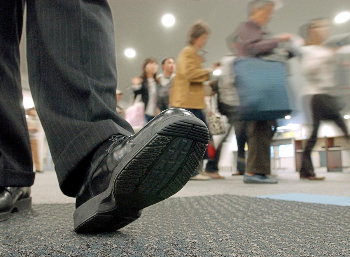 Tourists walk on a mat covered with an antiseptic solution to clean the soles of their shoes upon arrival at the Chubu International Airport in Japan.