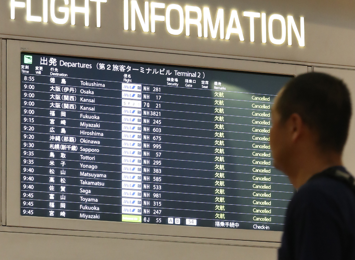 A man looks at the flight information board at the Haneda International airport in Tokyo.