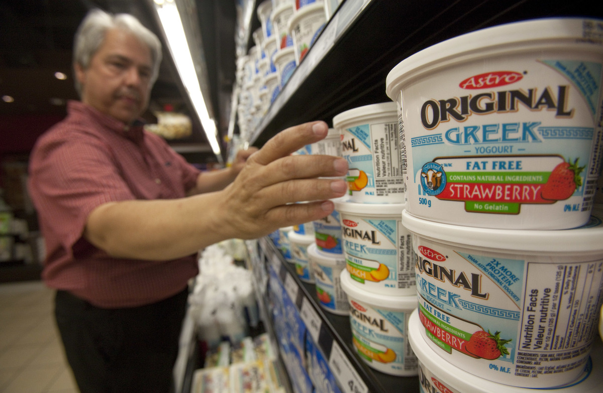 Dairy manager stocks Greek yogurt at a grocery store.