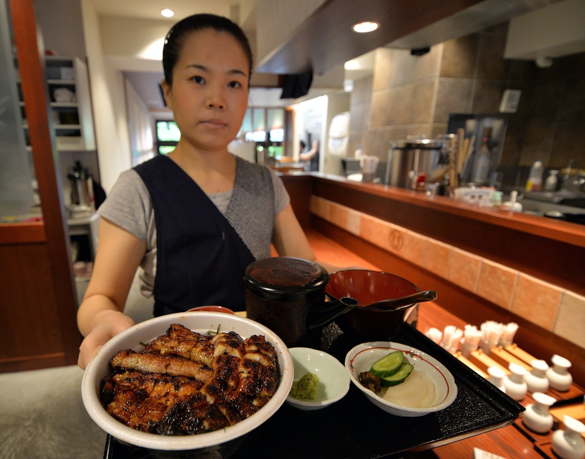 An employee of a Japanese grilled eel restaurant Unatetsu serves a dish in Tokyo.
