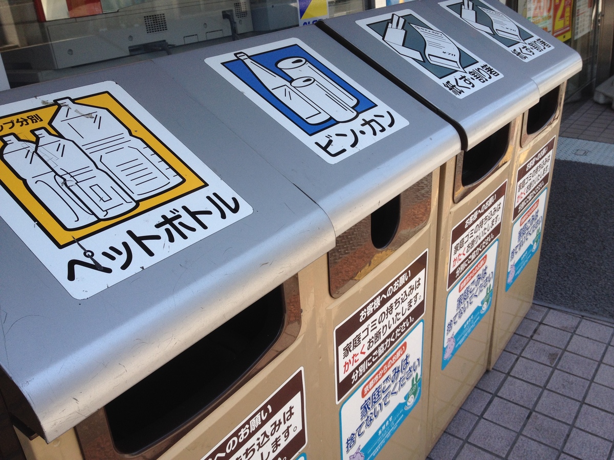 Trash cans and recycling bins line a street in Japan.
