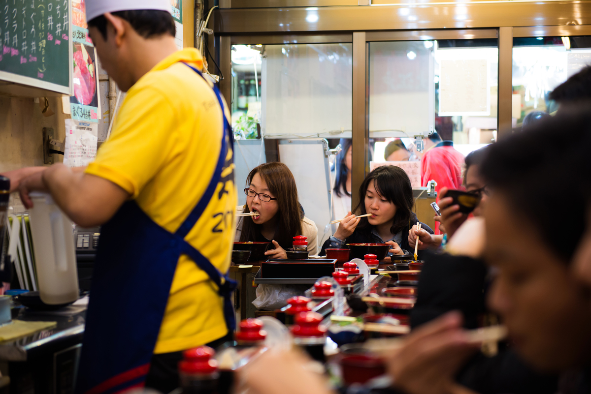 People eat at a Japanese sashimi restaurant as a chef prepares meals.