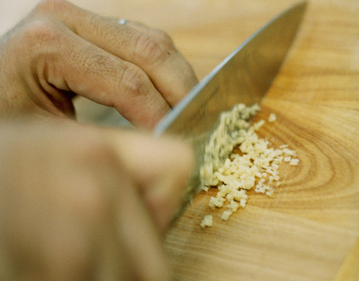 A chef minces fresh ginger for a sauce.