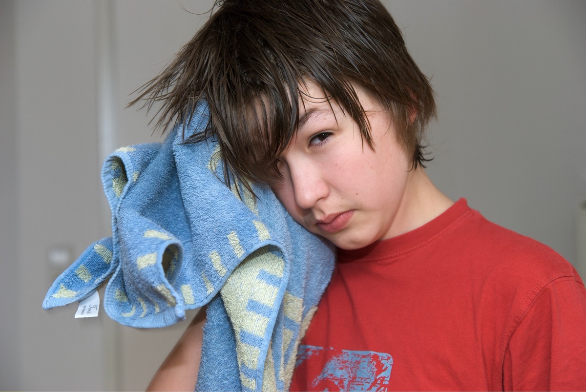 A boy dries his hair with a towel.