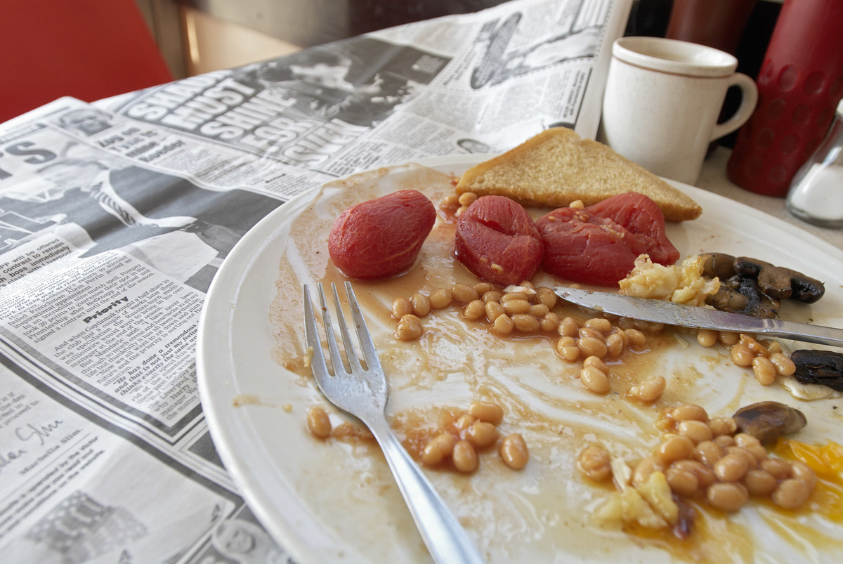 Refried beans are on a breakfast plate on a cafe table.