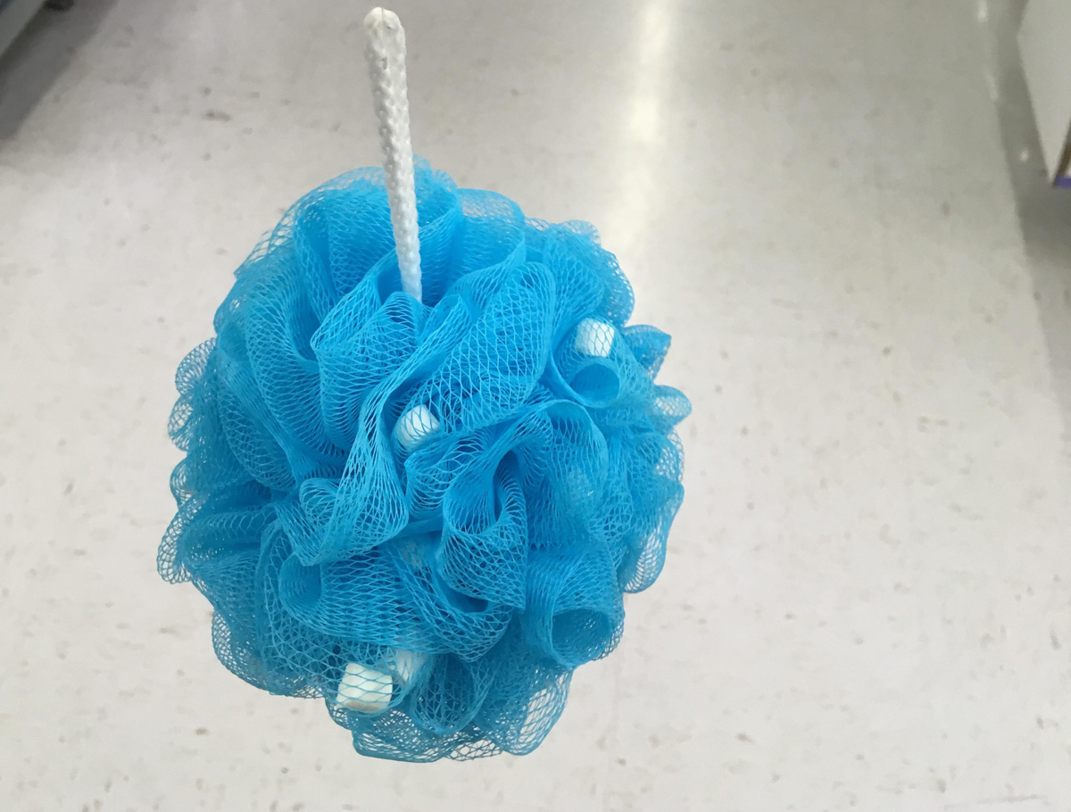 A blue loofah with soap beads inside of it is inside of a store.