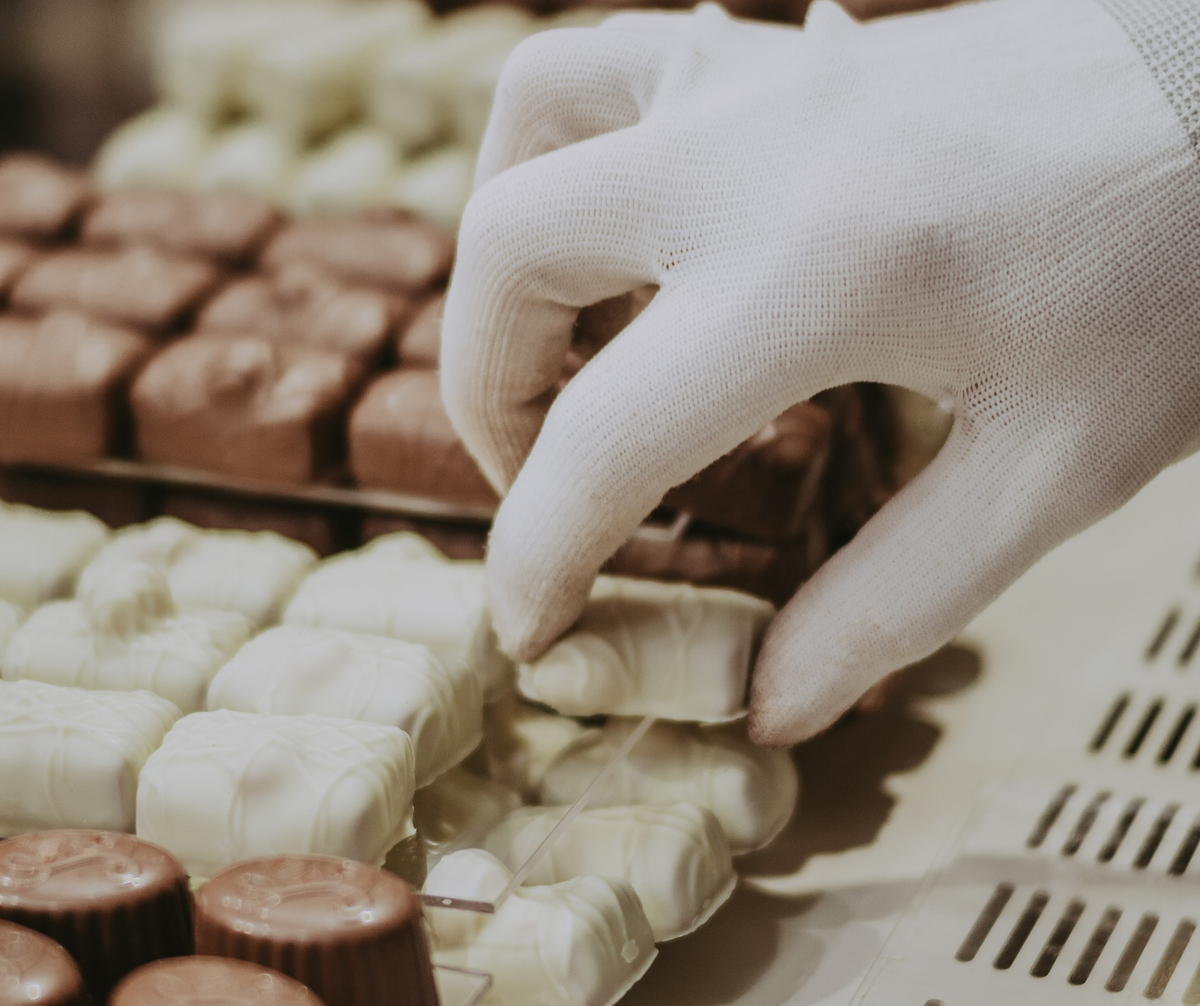 A person picks white chocolate from a stack of chocolates.