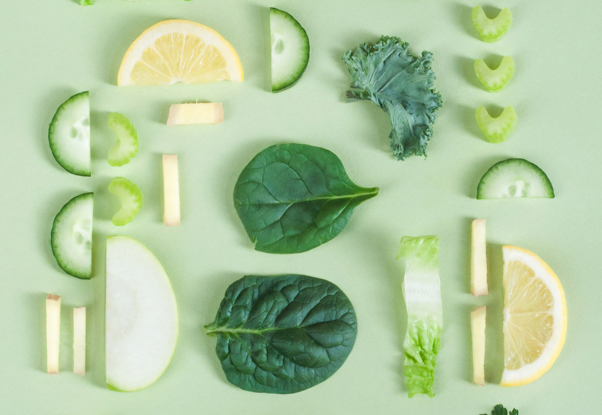 Green and yellow fruits and vegetables are arranged against a mint-colored background.