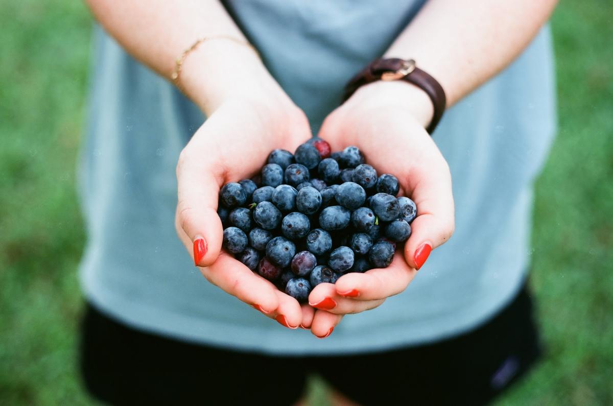 Woman with painted nails holds out blueberries.
