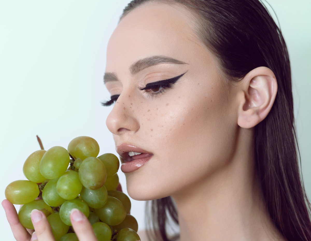 Woman holds green grapes to eat.