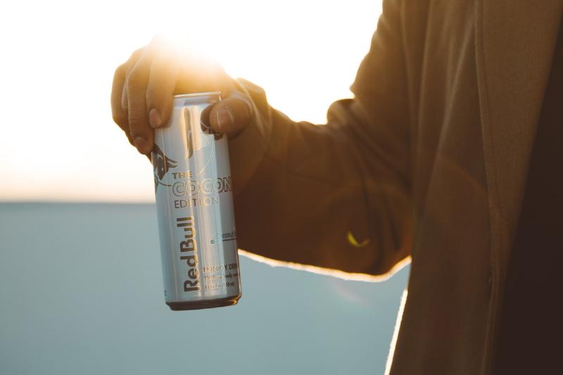 A man holds a can of Red Bull against the sunlight.