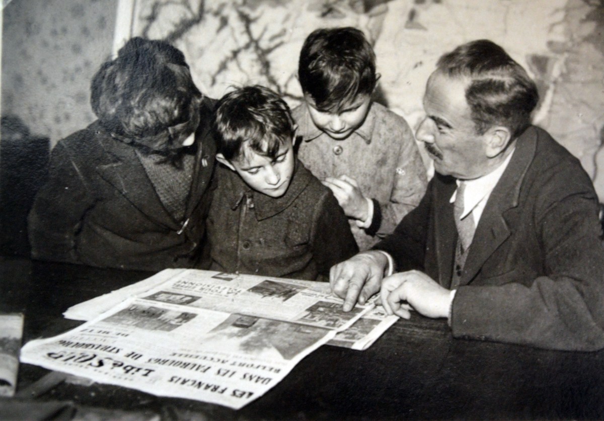 French family reads newspaper outlining the liberation of towns in Alsace Lorraine 1944.
