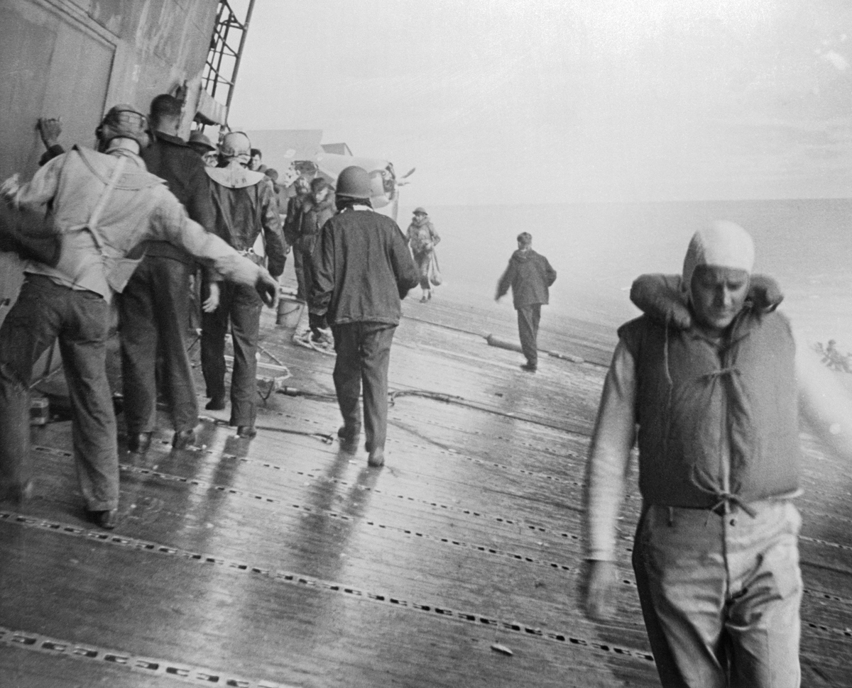 Navy soldiers attend the U.S.S. Yorktown aircraft carrier listing badly after she had been hit by bombs and torpedoes in the Battle of Midway.