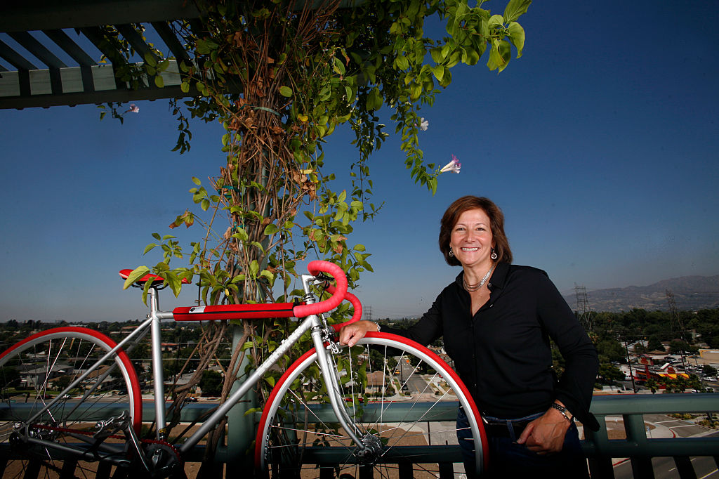 A woman poses with her bike on a balcony.