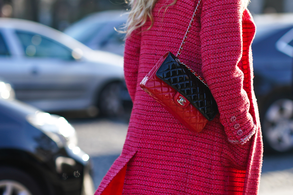 A woman walks through the streets of Paris in a pink tweed coat.