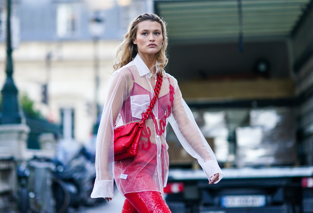 A woman wears pink under a sheer white shirt.