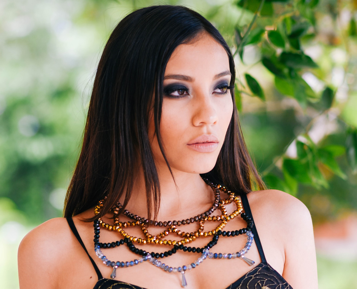 A model wears a large, elaborate beaded necklace.