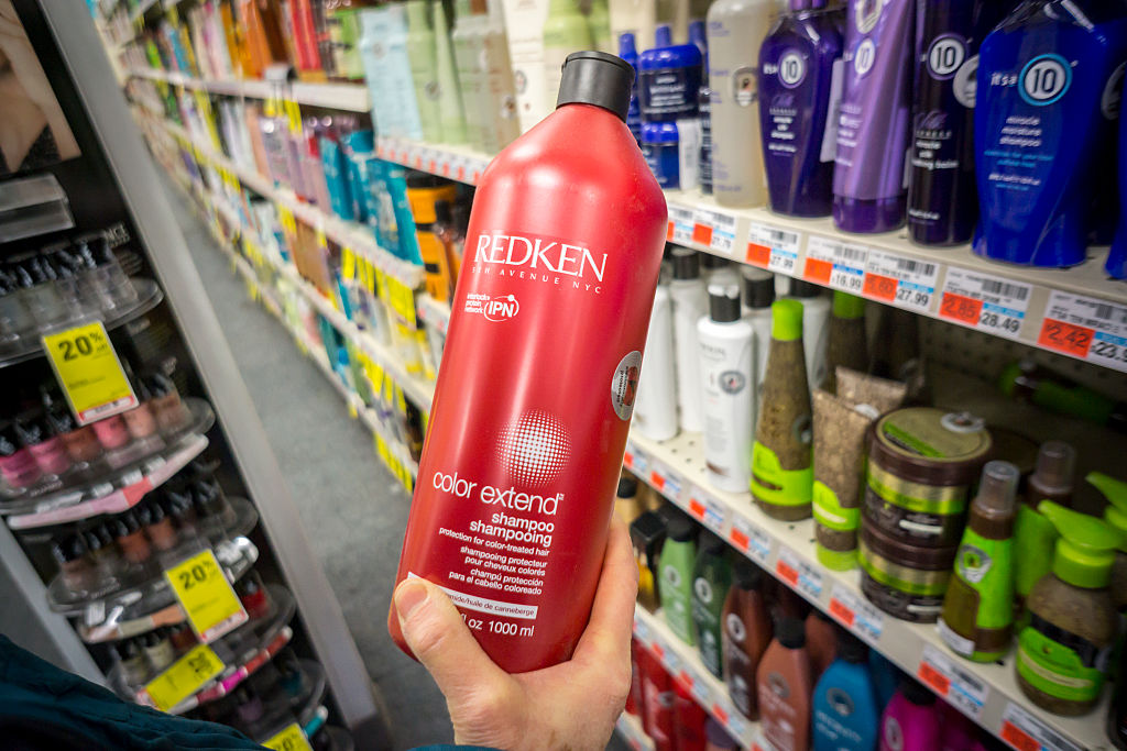 A shopper holds a bottle of Redken brand shampoov